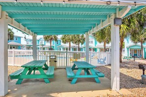 A covered picnic area with two green picnic tables, a trash can, and a white fence. - Blessed Getaway Stay for 10! (Port Aransas)