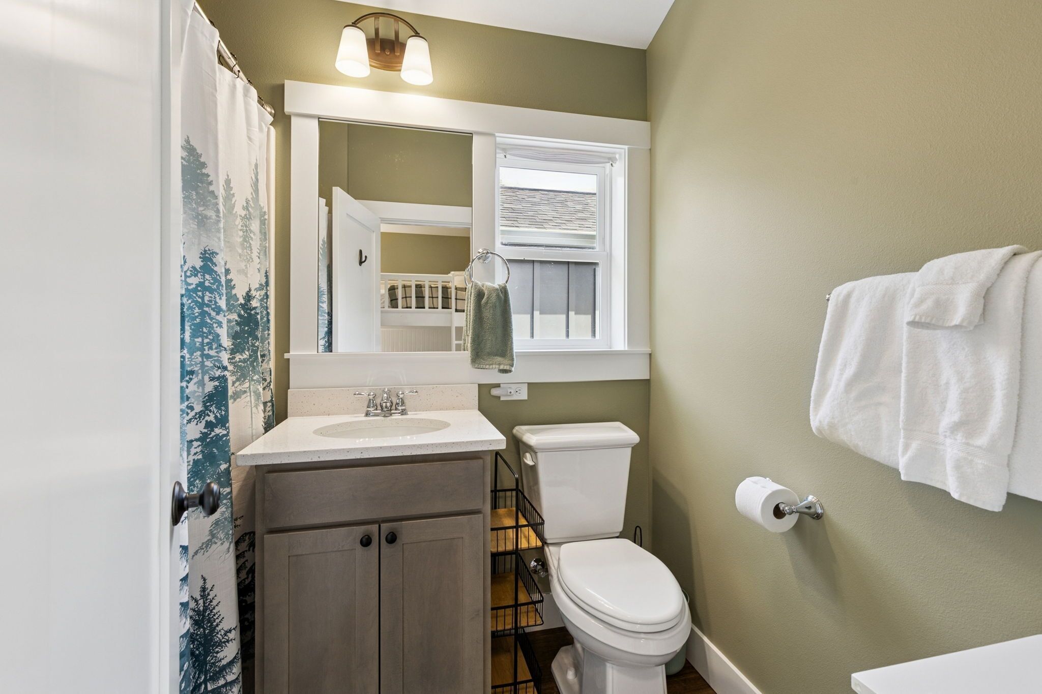 A bathroom with a toilet, sink, and mirror.