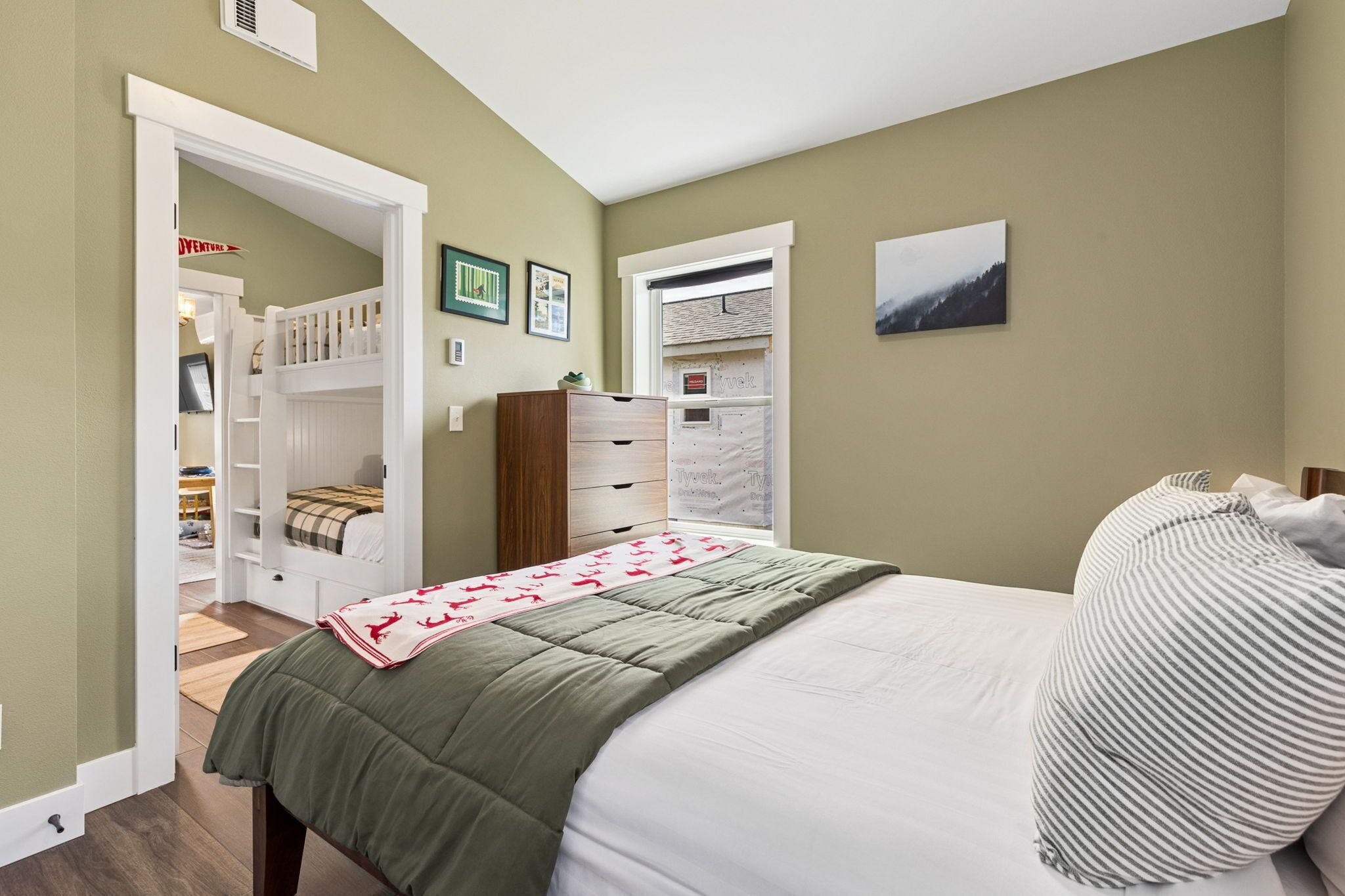 Une chambre à coucher avec un lit, une commode, un placard et une fenêtre.