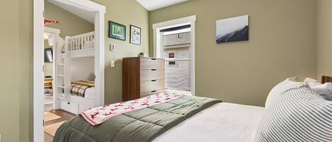 Une chambre à coucher avec un lit, une commode, un placard et une fenêtre.