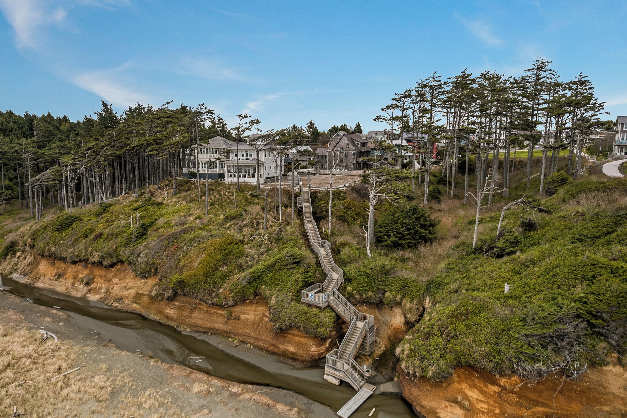 Een woongebied aan de kust met huizen, een kronkelend pad en een rivier.