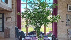 A dining area with a table set for six, surrounded by chairs, with a view of the outdoors. - Spacious and beautifully converted 18th century stone barn.  Pet-friendly! (Lullington)
