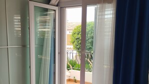 Un dormitorio con cama, armario y balcón con vistas.