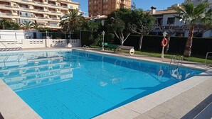 Una piscina con agua azul cristalina, rodeada por un solado de baldosas.