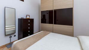Un dormitorio moderno con una cama, un tocador, un espejo y un armario.