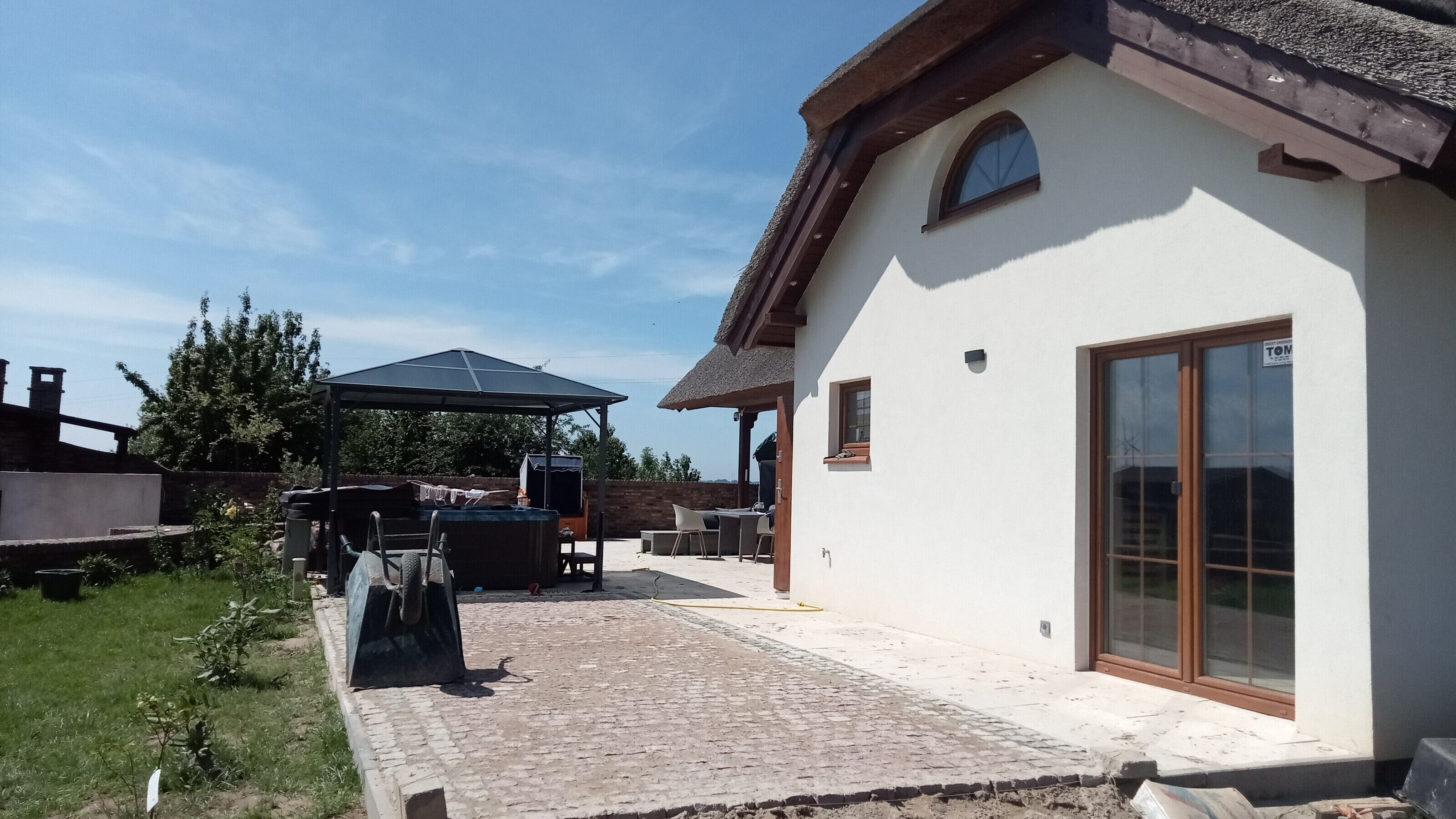 A house with a patio area, a covered outdoor seating area, and a large window.