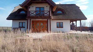 A two-story house with a thatched roof, a wooden balcony, and a large wooden door. - Luxury house: sauna, turk. Steam bath, Jacuzzi, whirlpool, fireplace - Polish Baltic Sea (Pogorzelica)