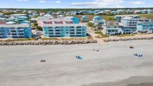 A coastal area with beachfront buildings, a sandy beach, and waves approaching the shore. - A Shore Oasis 1 Bedroom Villa (Carolina Beach)
