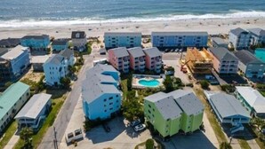 A coastal hotel with multiple buildings, a swimming pool, and a beach view. - A Shore Oasis 1 Bedroom Villa (Carolina Beach)