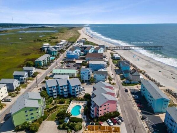 A coastal hotel with multiple buildings, a beach, and a pier.
