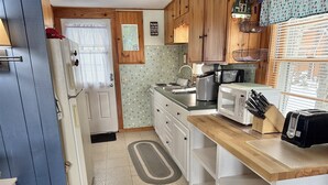 Eine kleine Küche mit Kühlschrank, Mikrowelle, Toaster und Spüle.