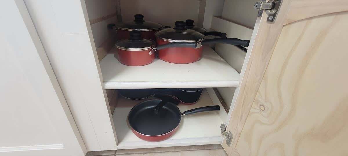 A kitchen cabinet with pots and pans.