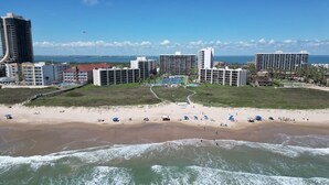 Un hotel sulla costa con diversi edifici, una spiaggia e una passeggiata sul mare.