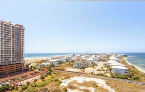Een kustgebied met woonhuizen, een uitgestrekt strand, een groot hotel en een weg naar het strand.