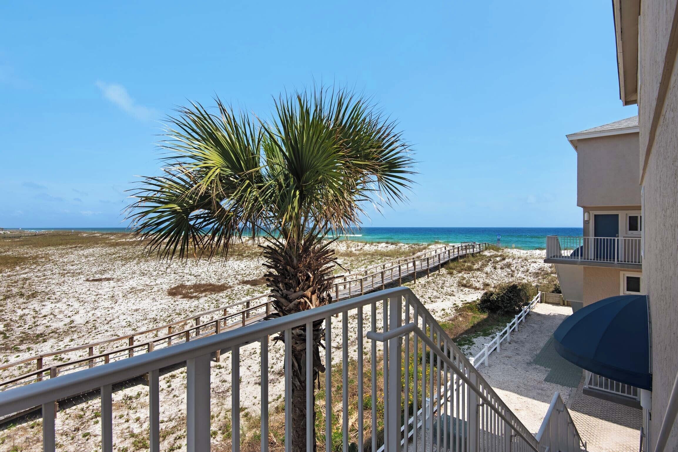 A balcony with a view of a sandy beach and the ocean.