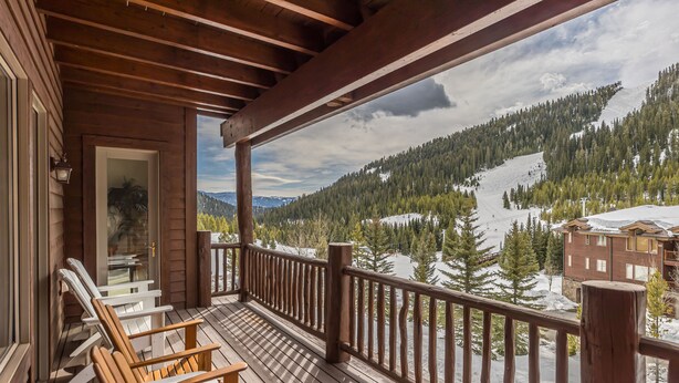 Un balcón de madera con vistas a un paisaje montañoso nevado.