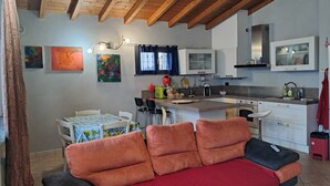 A cozy living area with a sofa, a dining table, and a kitchen with modern appliances. - Home Ross. (Fiorenzuola d'Arda)