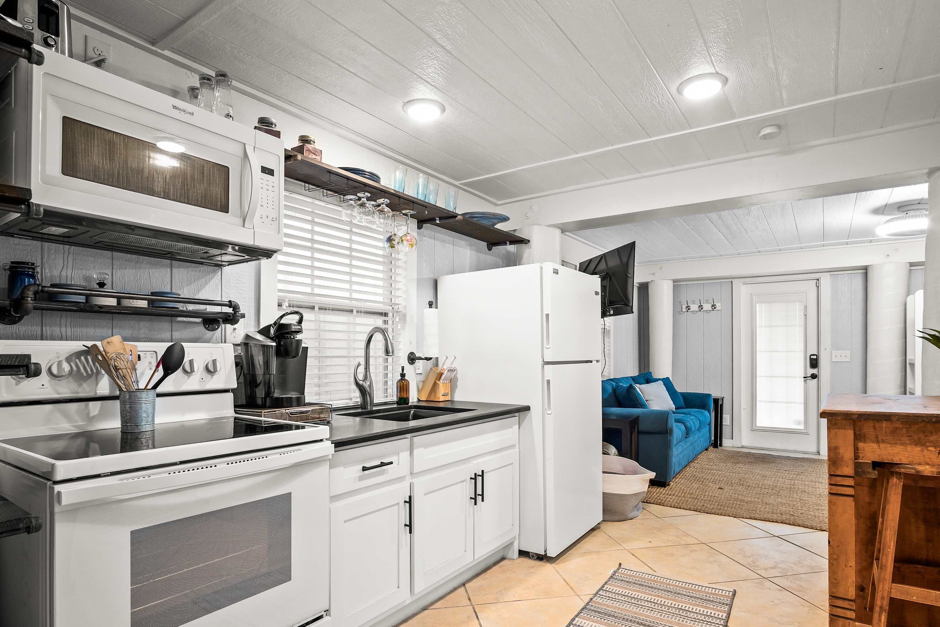 A modern kitchen with white cabinets, a built-in microwave, and a stainless steel range hood.