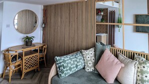 Une chambre à coucher aménagée dans un espace en hauteur, avec un lit superposé, un canapé, un miroir rond et un luminaire suspendu.
