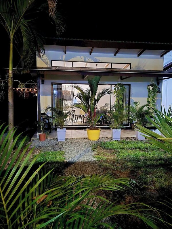 A modern building with large glass doors, surrounded by potted plants and a well-maintained garden.
