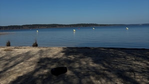A beach with a clear sky, calm water, and a distant shoreline.