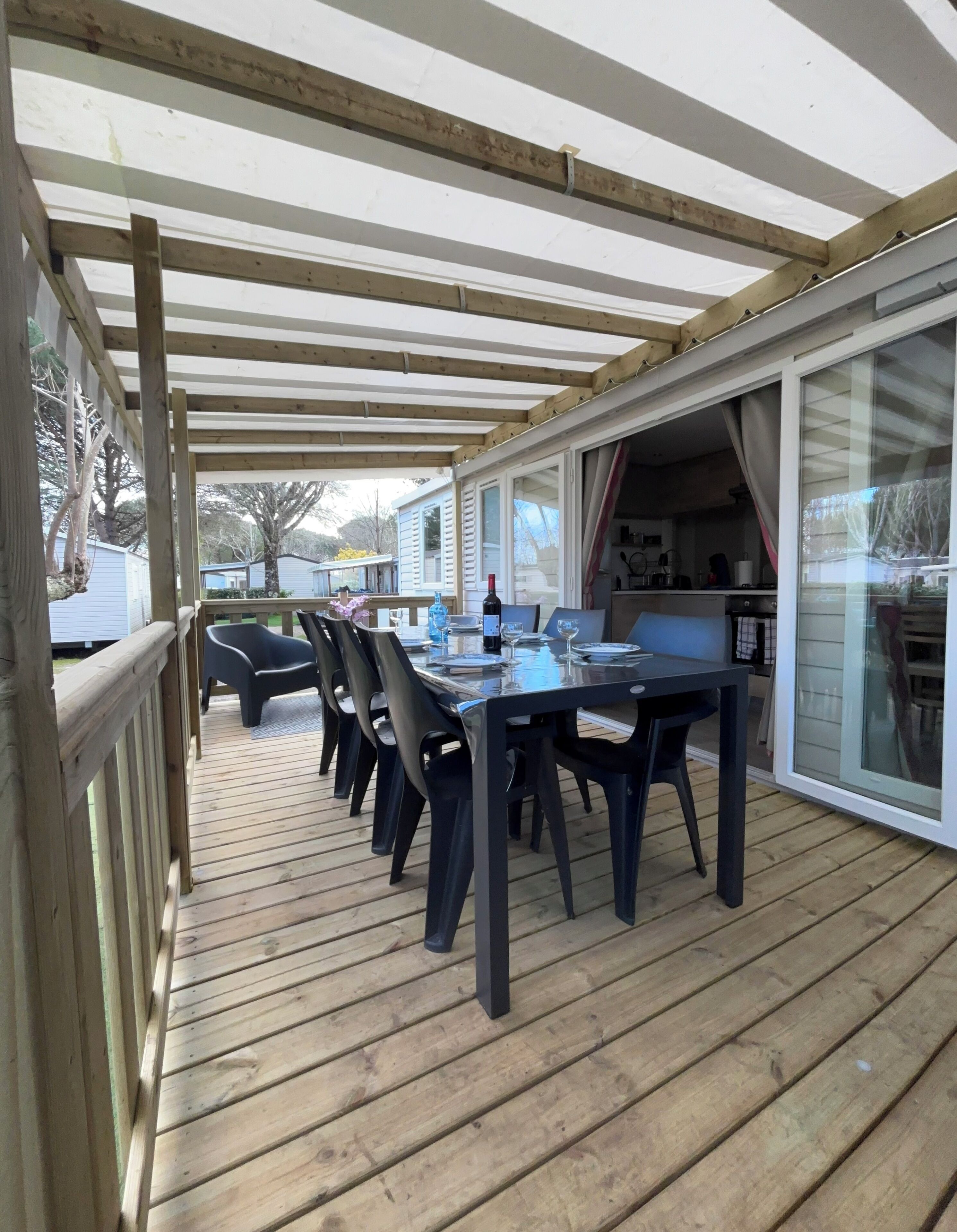 A covered outdoor dining area with a wooden deck, a table set for four, and chairs.