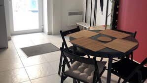 A dining area with a round table, black chairs, and a clock on the wall.