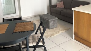 A modern living room with a grey sofa, a small round table, and a grey ottoman.