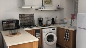 A compact kitchen with a central island, a washing machine, a microwave, and a gas stove.