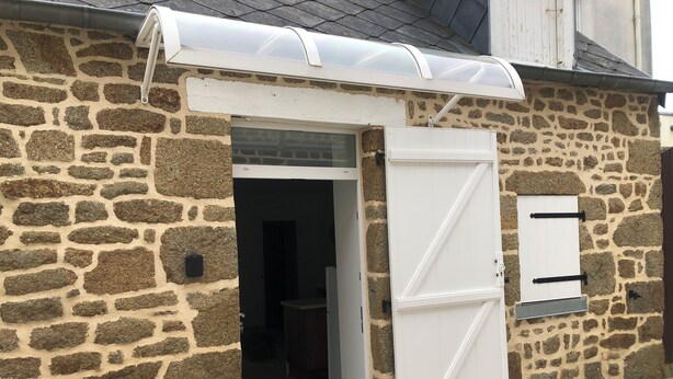 A stone building with a white door and a small window.
