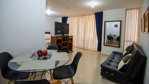 A living room with a sofa, a dining table with chairs, a TV, and a bookshelf. - Attractive apartment, well located, bright, comfortable, very complete, ventilated. (Bucaramanga)