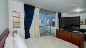 A hotel room with a bed, a television, a sliding glass door to the balcony, and framed artwork on the wall. - Attractive apartment, well located, bright, comfortable, very complete, ventilated. (Bucaramanga)