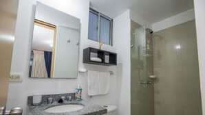 A bathroom with a granite countertop sink, a mirror, a towel rack, a shelf with a towel, and a glass-enclosed shower. - Attractive apartment, well located, bright, comfortable, very complete, ventilated. (Bucaramanga)