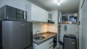 A compact kitchen with a stainless steel refrigerator, a microwave, a gas stove, and a sink. - Attractive apartment, well located, bright, comfortable, very complete, ventilated. (Bucaramanga)