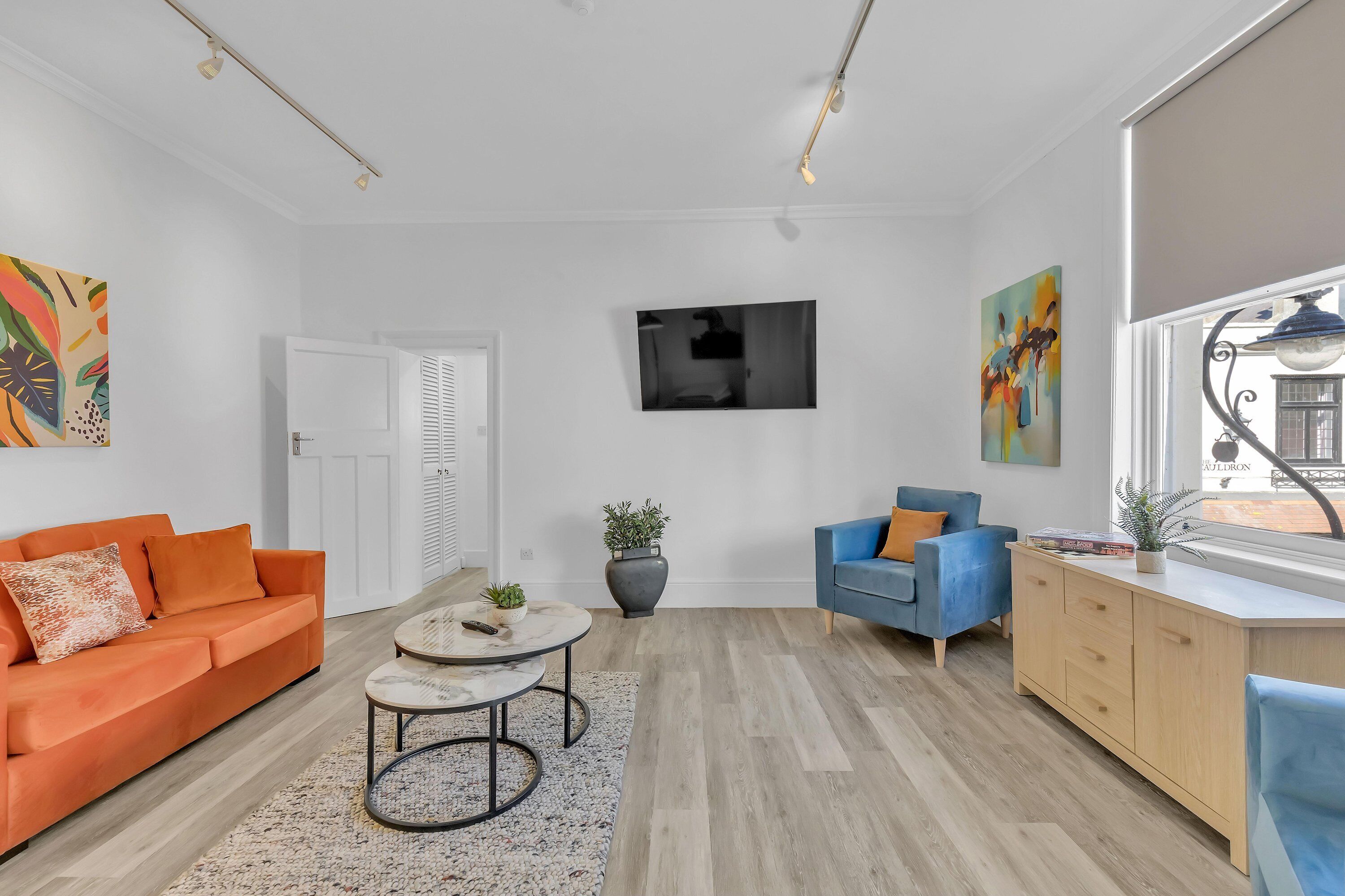 A modern living room with a sofa, coffee table, and a TV mounted on the wall.