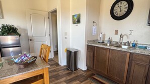 Una cocina con armarios de madera, un lavamanos y un reloj en la pared.