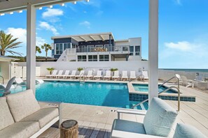 Un hôtel moderne doté d’une piscine, de chaises longues et offrant une vue sur l’océan.