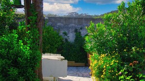 A stone pathway leading to a seating area surrounded by lush greenery and a view of a mountainous landscape. - Peaceful Farmhouse Retreat Near Nazaré | 3BR Countryside Stay Minutes to Beach (Quinta Nova, Famalicao, Portugal)