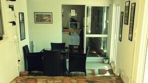 A room with a stone-patterned floor, a dining area with chairs and a table, and a kitchen area with appliances. - Peaceful Farmhouse Retreat Near Nazaré | 3BR Countryside Stay Minutes to Beach (Quinta Nova, Famalicao, Portugal)