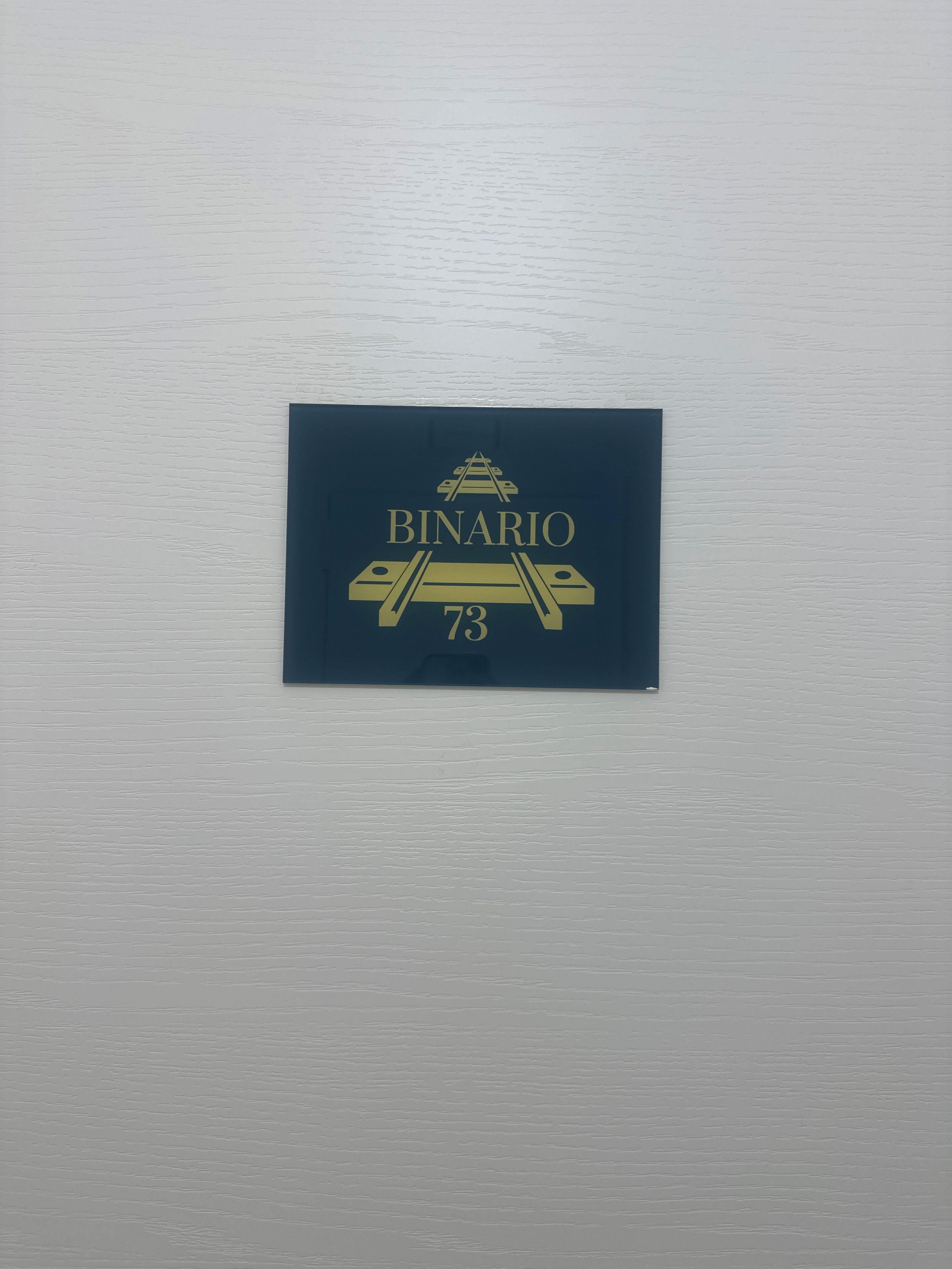 A wall-mounted sign with the text 'BINARIO 73' and a graphic of a bridge.