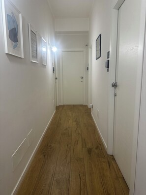 A hallway with wooden flooring, white walls, and doors leading to rooms. - Binario 73 (Naples)