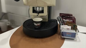 A coffee machine with a drip tray, a coffee pod holder, and a cup of coffee. - Binario 73 (Naples)