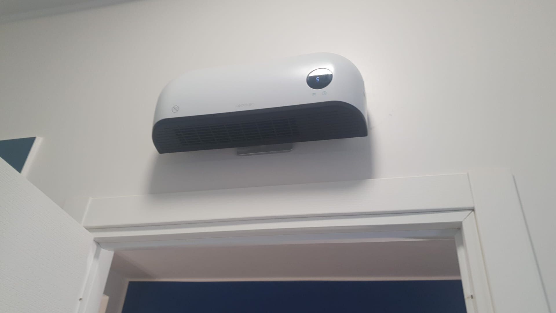 A white air conditioning unit mounted on a wall above a doorway.