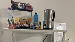 A kitchenette with a coffee maker, kettle, and various food items on the shelves. - Binario 73 (Naples)