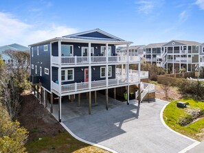 A multi-story building with a balcony on the ground floor, a covered walkway, and a pool area. - Experience luxury at Psalm Tree, a spacious 6-bedroom, 6-bathroom ocean view retreat (Oak Island)