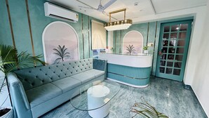 Una sala de estar moderna con un sofá azul, una mesa de centro de vidrio y un mostrador de atención al cliente.