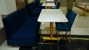 Un comedor con sofás azules y mesas de mármol blanco.