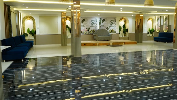 Un vestíbulo moderno con piso de mármol pulido, sofás azules y plantas decorativas.