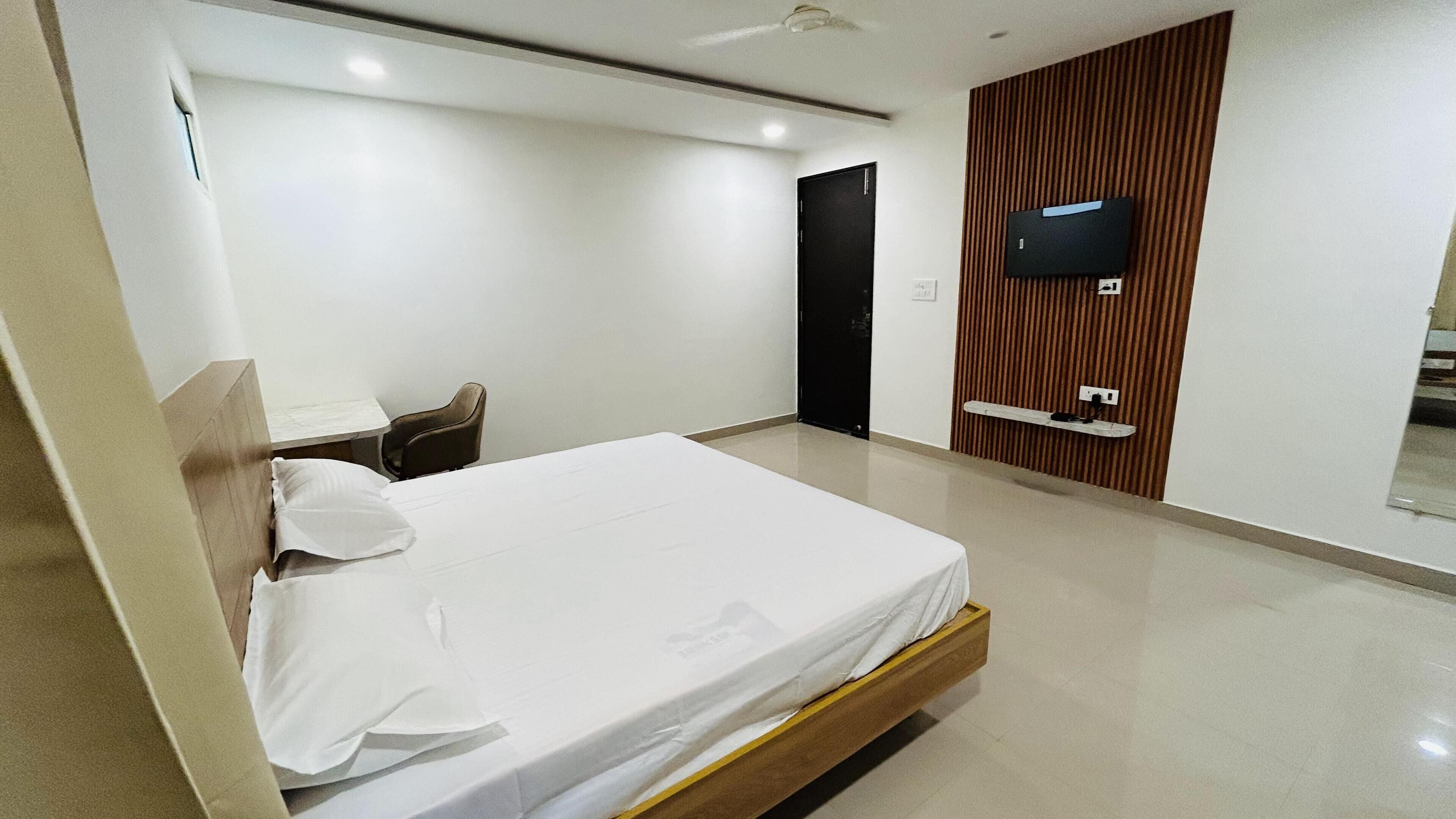 Una habitación de hotel moderna con una cama grande, un escritorio y un televisor montado en la pared.