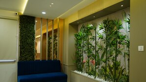 Zona de recepción con un sofá azul, un jardín vertical en la pared y un diseño de paneles de madera.